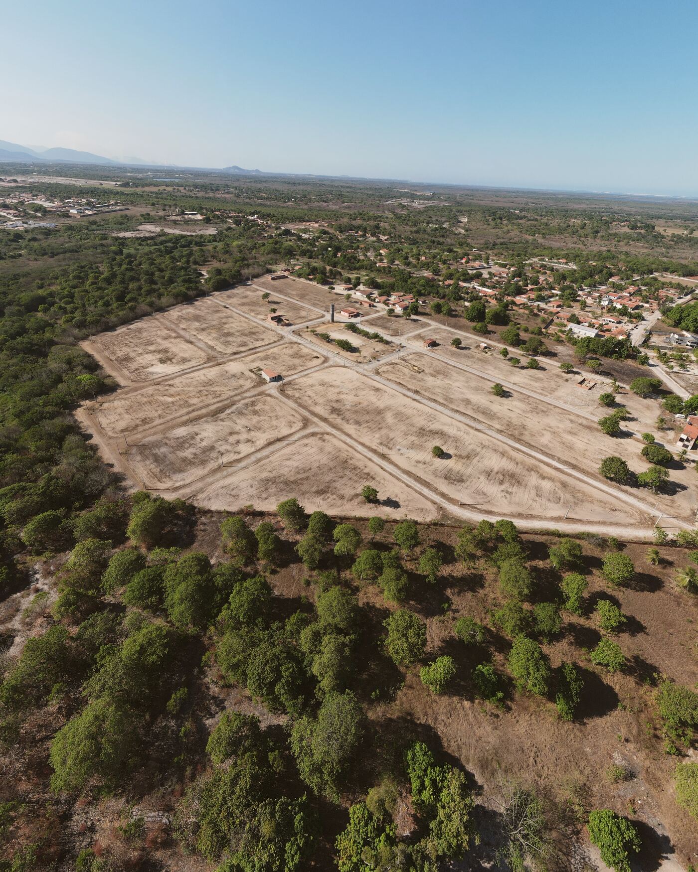 Vista aérea do Villa Dourados: quadras abertas entre a vegetação, com Horizonte no horizonte